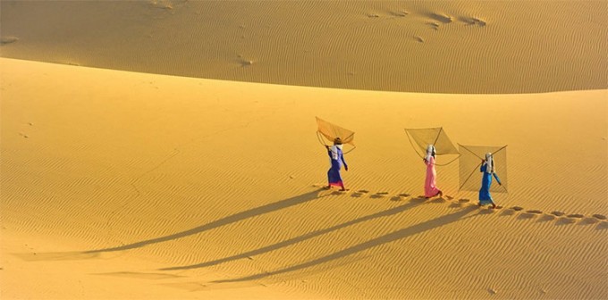 Vietnamese women cross the sand dunes