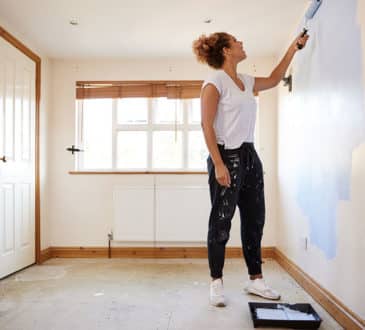 Woman Decorating Room In New Home Painting Wall