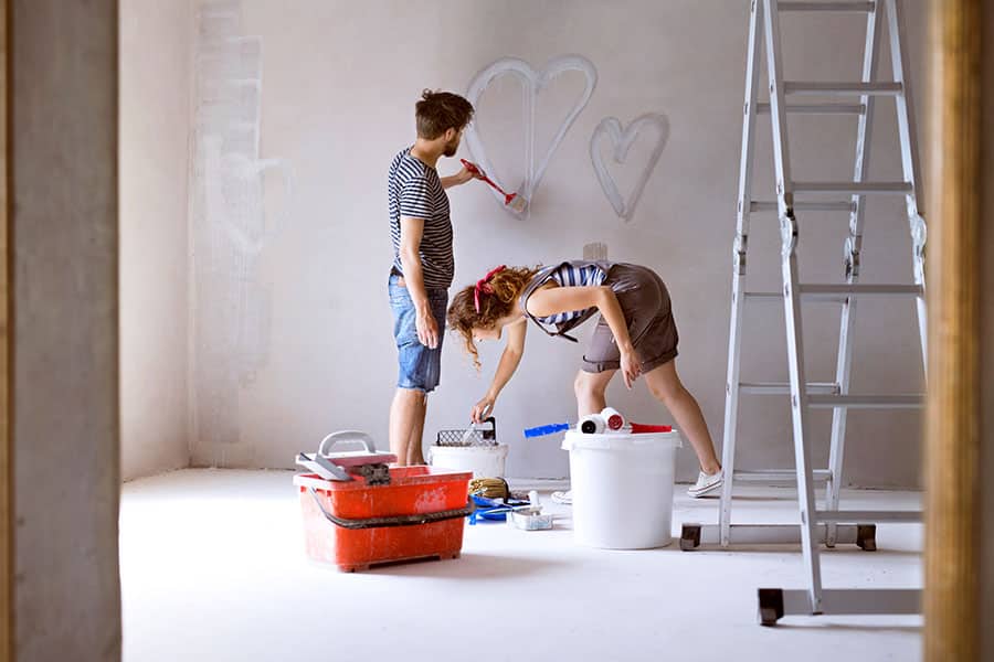 Couple painting hearts on the wall in their house